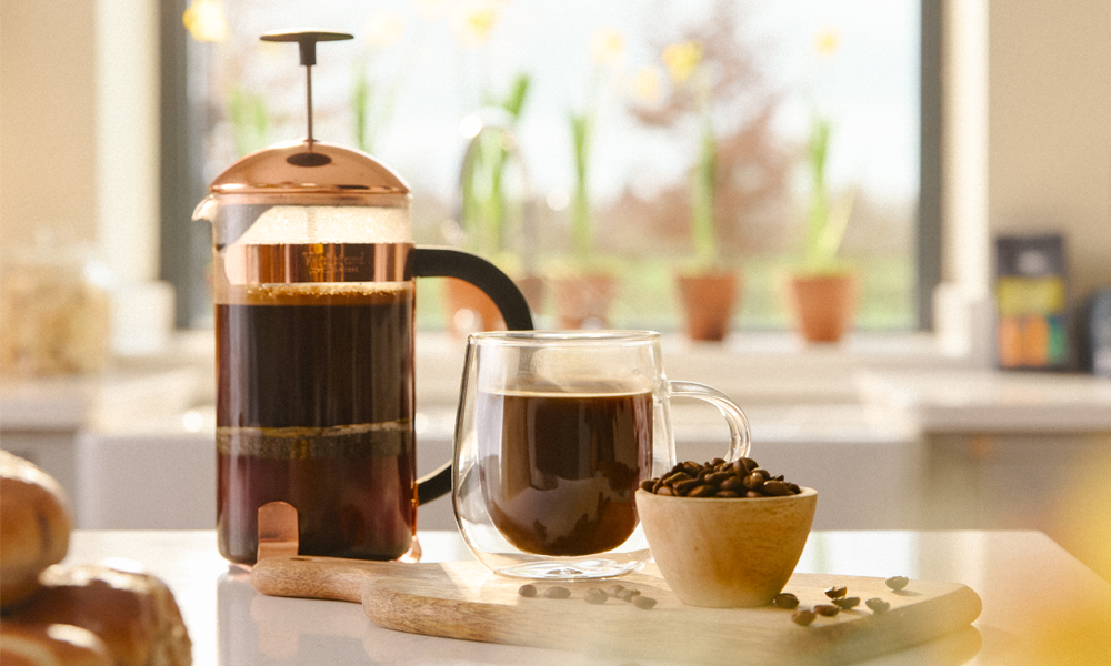 Various coffee equipment and drinks on a kitchen side with a bowl full of whittard coffee beans